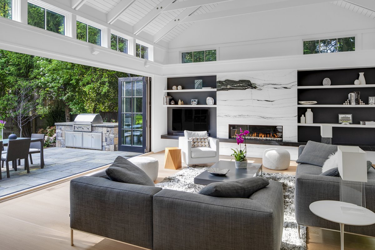 family room with accordion doors and modern marble fireplace© Jacob Lilley Architects Wellesley, MA